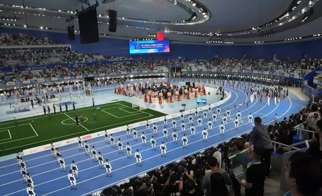 Spectator looking robots perform during the opening ceremony of the World Humanoid Robot Games in Beijing, Saturday, Aug. 22, 2026. (AP Photo/Achmad Ibrahim)