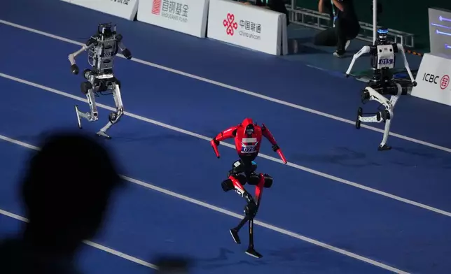 Robots compete in the 100m race during the opening ceremony of the World Humanoid Robot Games in Beijing, Saturday, Aug. 22, 2026. (AP Photo/Achmad Ibrahim)