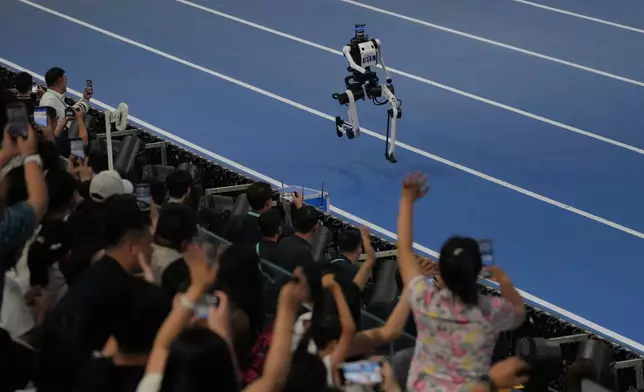 Spectators cheer a robot competing in the 1500m during the World Humanoid Robot Games in Beijing, Sunday, Aug. 23, 2026. (AP Photo/Achmad Ibrahim)