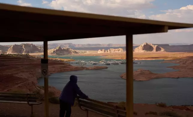 FILE - A person stands at an overlook near the Wahweap Marina on Lake Powell at the Glen Canyon National Recreation Area, July 15, 2026, near Page, Ariz. (AP Photo/John Locher, File)