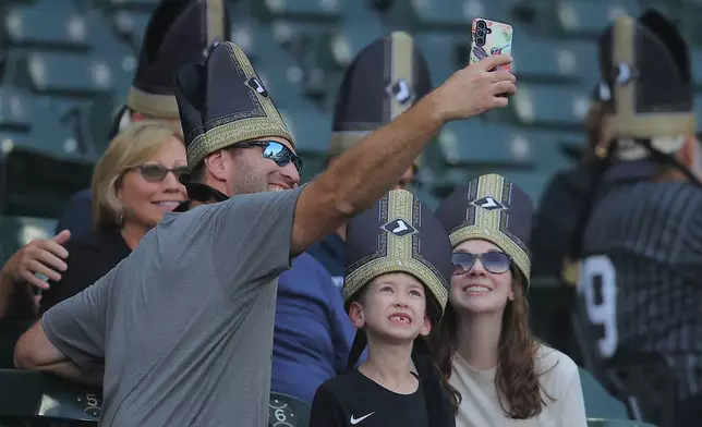 A group of fans wear a promotional pope hat prior to a baseball game between the Cincinnati Reds and Chicago White Sox, Tuesday, Aug. 11, 2026, in Chicago. (AP Photo/Melissa Tamez)