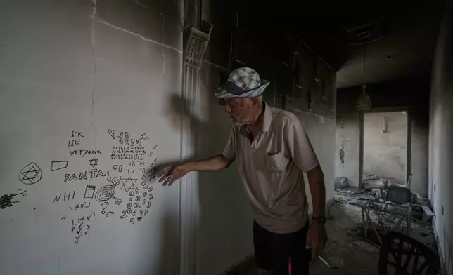 A Lebanese man points to Hebrew writing left by Israeli soldiers inside his destroyed home in the village of Zawtar al-Gharbieh, southern Lebanon, Wednesday, Aug. 5, 2026.(AP Photo/Mohammed Zaatari)