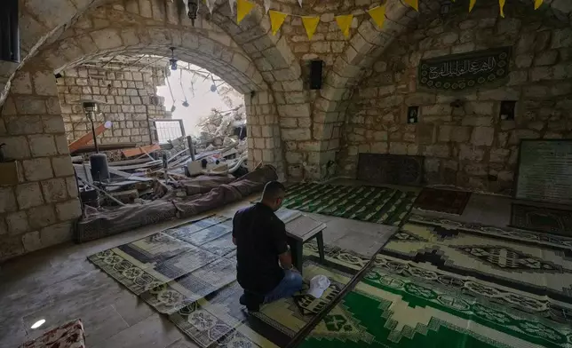 A Lebanese man reads a copy of the Quran inside a damaged house in the village of Zawtar al-Gharbieh, south Lebanon, Wednesday, Aug. 5, 2026. (AP Photo/Mohammed Zaatari)