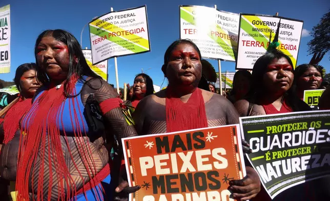 FILE - An Indigenous woman marches with a sign that reads in Portuguese "More fish, less mining," during the 20th annual Free Land Indigenous Camp in Brasilia, Brazil, April 23, 2024. (AP Photo/Luis Nova, File)