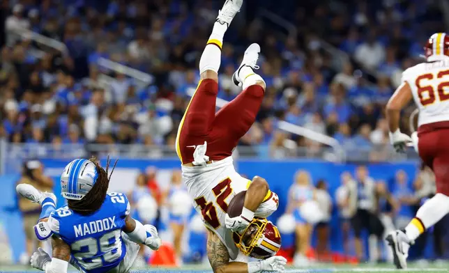 Washington Commanders running back Craig Reynolds (24) is upended by Detroit Lions cornerback Avonte Maddox (29) during a preseason NFL football game, Saturday, Aug. 22, 2026, in Detroit. (AP Photo/Rey Del Rio)