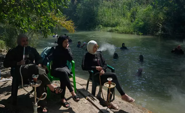 Women smoke waterpipes as they sit by the Litani River in the village of Qaaqaaiet al-Jisr, southern Lebanon, Sunday, Aug. 23, 2026. (AP Photo/Mohammed Zaatari)