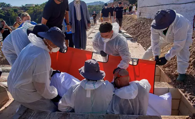 Funeral workers place into a grave the body of a migrant who died while trying to cross from Morocco into the Spanish exclave of Ceuta, Friday, Aug. 21, 2026. (AP Photo/Antonio Sempere)