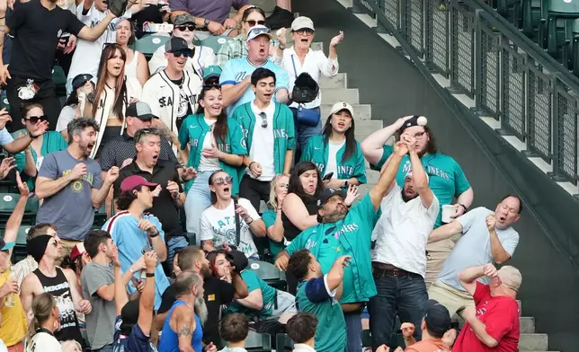 Fans vie for the solo home run hit by Seattle Mariners' Cal Raleigh during the second inning of a baseball game against the Philadelphia Phillies, Tuesday, Aug. 25, 2026, in Seattle. (AP Photo/Lindsey Wasson)