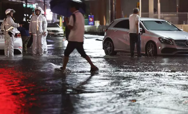 Record-breaking torrential rain floods a road, causing a car to stall, in Ichikawa, Chiba prefecture, Japan, on Thursday, Aug. 13, 2026. (Kyodo News via AP)