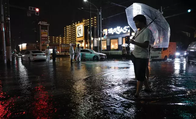Torrential rain floods a road, causing a car to stall, in Ichikawa, Chiba prefecture, Japan, on Thursday, Aug. 13, 2026. (Kenzaburo Fukuhara/Kyodo News via AP)