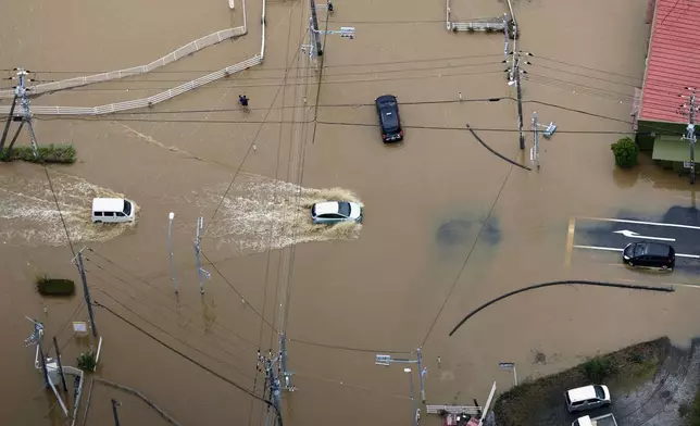 Cars make their way through flooded road after heavy rain in Oamishirasato, Chiba prefecture, Japan, Friday, Aug. 14, 2026. (Kota Endo/Kyodo News via AP)