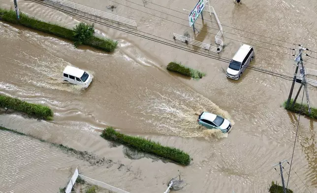Cars make their way through flooded road after heavy rain in Oamishirasato, Chiba prefecture, Japan, Friday, Aug. 14, 2026. (Kota Endo/Kyodo News via AP)