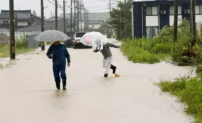 People walk through a street flooded due to a heavy rain in Hakui, Ishikawa prefecture, Japan Thursday, Aug. 27, 2026. (Yusuke Ogata/Kyodo News via AP)