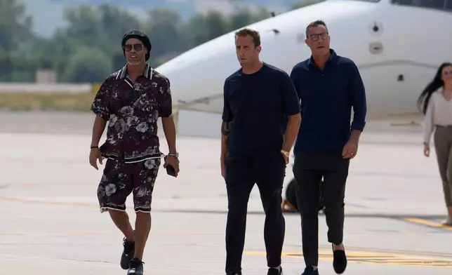 Former soccer star Ronaldinho, left, flanked by Ravenna president Igniazio Cipriani, center, arrives at the airport ahead the Ravenna Serie C, 2026 soccer team presentation, joining the club as a technical coach and playing in one match in Ravenna, Italy, Thursday, Aug. 20, 2026. (AP Photo/Luca Bruno)