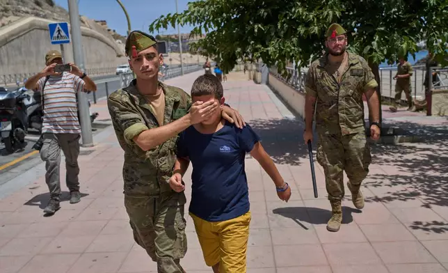 A 12-year-old unaccompanied minor who crossed into Spain is escorted by a Spanish soldier to the Spain-Morocco border from the Spanish enclave of Ceuta, Monday, Aug. 3, 2026. The forced deportation of the unaccompanied minor was stopped by a high-ranking official a few meters before the child reached the border after residents and journalists said the migrant was a minor. (AP Photo/Bernat Armangue)