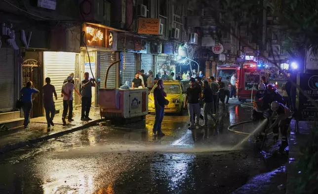 Residents watch as Syrian firefighters clean the site of an explosion in the Jaramana suburb, home to a large Druze population, in Damascus, Syria, Thursday, Aug. 6, 2026. (AP Photo/Omar Albam)