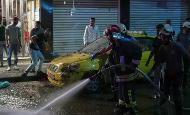 Residents watch as Syrian firefighters clean the site of an explosion in the Jaramana suburb, home to a large Druze population, in Damascus, Syria, Thursday, Aug. 6, 2026. (AP Photo/Omar Albam)