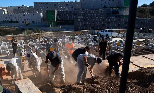 Funeral workers bury migrants who died while trying to cross from Morocco into the Spanish exclave of Ceuta, Friday, Aug. 21, 2026. (AP Photo/Antonio Sempere)