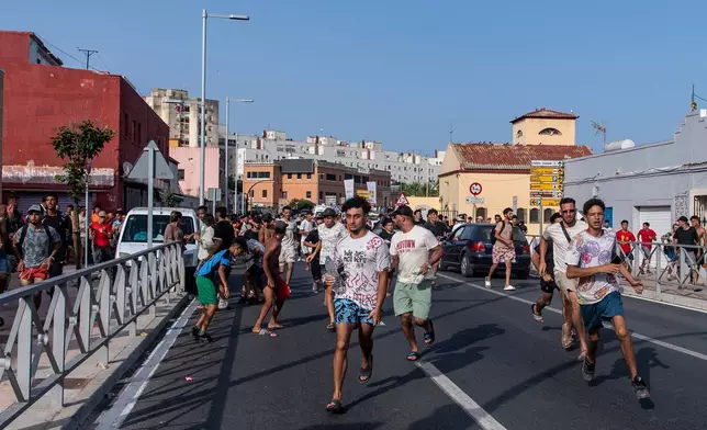 Migrants run from Spanish police officers after crossing from Morocco into the Spanish enclave of Ceuta, Friday, July 31, 2026. (AP Photo/Antonio Sempere)