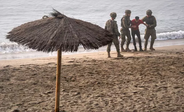 Spanish army soldiers assist a migrant who swam from Morocco to the Spanish enclave of Ceuta, Saturday, Aug. 1, 2026. (AP Photo/Antonio Sempere)