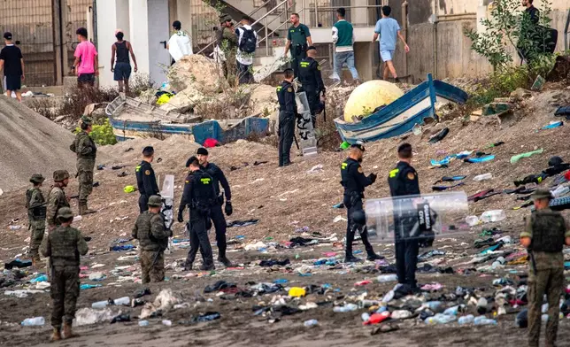 Spanish army soldiers and Guardia Civil officers stand guard as migrants return to Morocco from the Spanish enclave of Ceuta, Saturday, Aug. 1, 2026. (AP Photo/Antonio Sempere)