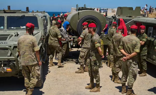 Migrants who crossed into Spain from Morocco collect water distributed by Spanish soldiers in the Spanish enclave of Ceuta, Sunday, Aug. 2, 2026. (AP Photo/Bernat Armangue)