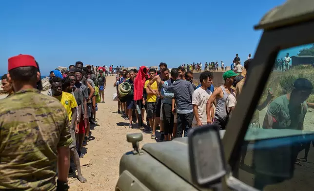 Migrants who crossed into Spain from Morocco line up for water distributed by Spanish soldiers in the Spanish enclave of Ceuta, Sunday, Aug. 2, 2026. (AP Photo/Bernat Armangue)