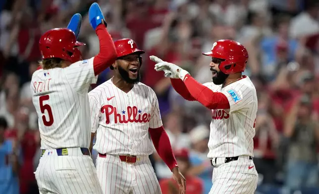 Philadelphia Phillies' Derek Hill, from right, celebrates with Bryan de la Cruz and Bryson Stott after hitting a grand slam against Washington Nationals pitcher Tom Cosgrove during the seventh inning of a baseball game Monday, Aug. 3, 2026, in Philadelphia. (AP Photo/Matt Slocum)