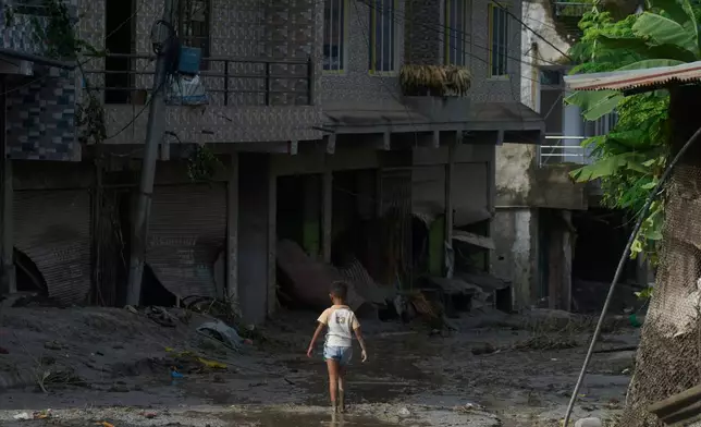 A child walks in mud in the aftermath of a flash floods in Devighat in the Nuwakot district in Nepal, Thursday, Aug 27, 2026. (AP Photo/Niranjan Shrestha)