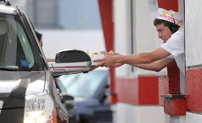 FILE - A customer receives her burger and fries from the drive-thru at In-N-Out Burger on Friday, June 11, 2010, in the Hollywood area of Los Angeles. (AP Photo/Adam Lau, File)