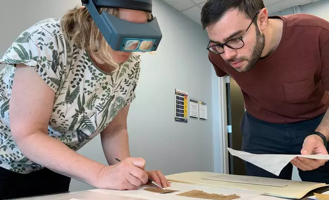 Papyrus Conservation Summer Seminar instructor Marieka Kaye inspects student Mauro Castiello's papyrus fragment and provides him with feedback on his preservation work at the University of Michigan Thursday, Aug. 6, 2026, in Ann Arbor, Mich. (AP Photo/Mike Householder)