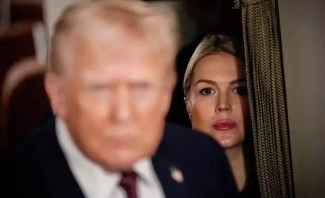 FILE - White House press secretary Karoline Leavitt watches as President Donald Trump speak to reporters while in flight on Air Force One to Joint Base Andrews, Md., Jan. 11, 2026. (AP Photo/Julia Demaree Nikhinson, File)