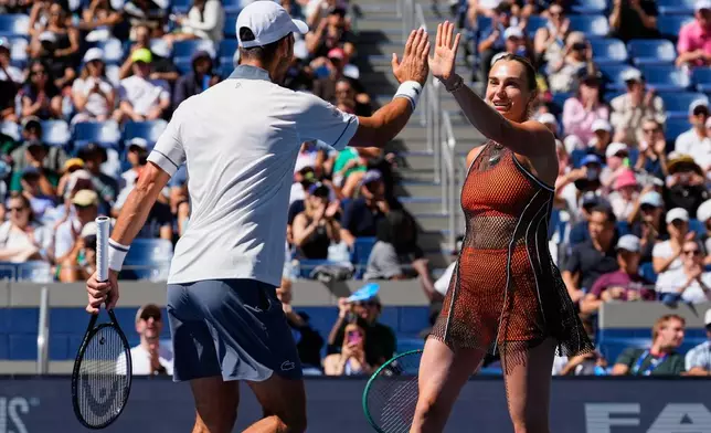 Novak Djokovic, of Serbia, left, and Aryna Sabalenka, of Belarus, high-five during a mixed doubles match at the U.S. Open tennis championships, Tuesday, Aug. 25, 2026, in New York. (AP Photo/Yuki Iwamura)