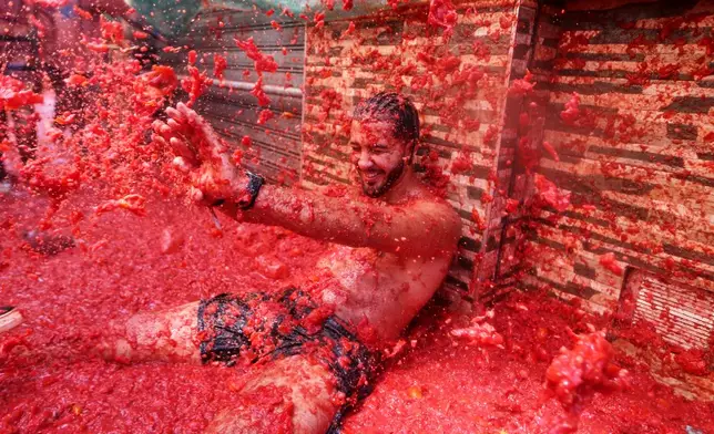 A reveler takes part in the annual "Tomatina" tomato fight fiesta, in the village of Bunol near Valencia, Spain, Wednesday, Aug. 26, 2026. (AP Photo/Alberto Saiz)
