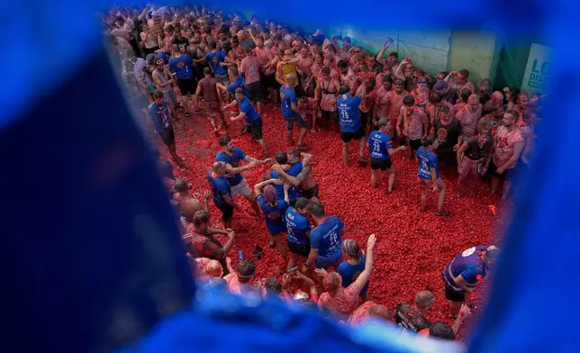 Revelers throw tomatoes at each other during the annual "Tomatina" tomato fight fiesta, in the village of Bunol near Valencia, Spain, Wednesday, Aug. 26, 2026. (AP Photo/Alberto Saiz)