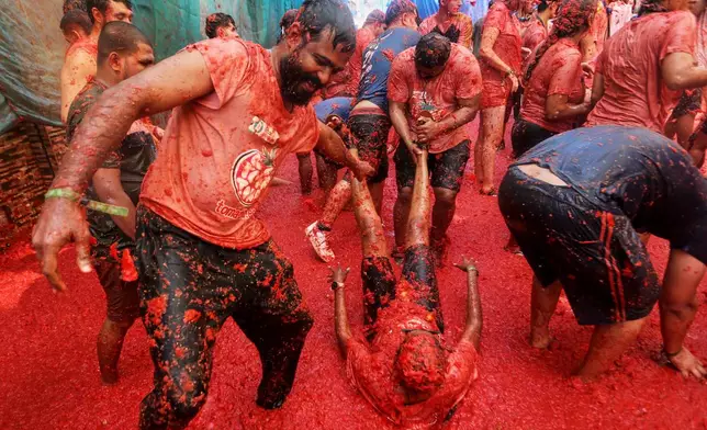 Revelers throw tomatoes at each other during the annual "Tomatina" tomato fight fiesta, in the village of Bunol near Valencia, Spain, Wednesday, Aug. 26, 2026. (AP Photo/Alberto Saiz)