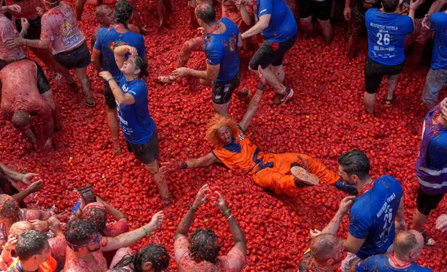 Revelers throw tomatoes at each other during the annual "Tomatina" tomato fight fiesta, in the village of Bunol near Valencia, Spain, Wednesday, Aug. 26, 2026. (AP Photo/Alberto Saiz)