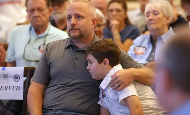 Rep. Russell Fry, R-S.C., left, sits with his son James at a candidate event for hopefuls vying in a special Republican primary to replace the late Sen. Lindsey Graham, R-S.C., on November ballots, Saturday, Aug. 8, 2026, in Florence, S.C. (AP Photo/Meg Kinnard)