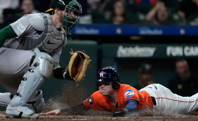 Houston Astros' Nick Allen scores behind Athletics catcher Jonah Heim during the fifth inning of a baseball game Friday, Aug. 21, 2026, in Houston. (AP Photo/Kevin M. Cox)
