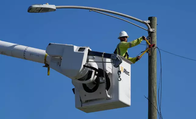 An electrical worker repairs power lines along a street in Gary, Ind, Thursday, Aug. 20, 2026, more than a week after a deadly storm passes through the area. (AP Photo/Nam Y. Huh)