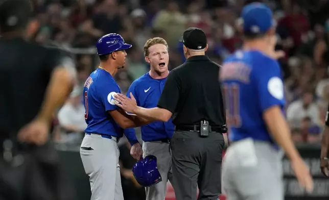 Chicago Cubs' Pete Crow-Armstrong, center, and Cubs third base coach Quintin Berry (0) argue with umpire Lance Barrett during the sixth inning of a baseball game against the Arizona Diamondbacks, Wednesday, Aug. 26, 2026, in Phoenix. (AP Photo/Ross D. Franklin)