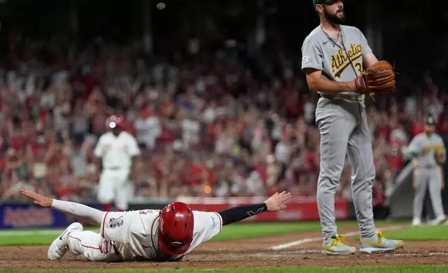Cincinnati Reds' Sal Stewart, left, reacts after diving across home plate to score the go-ahead run on a wild pitch by Athletics pitcher Hogan Harris, right, during the eight inning of a baseball game in Cincinnati, Tuesday, Aug. 4, 2026. (AP Photo/Carolyn Kaster)