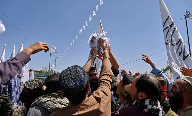 Taliban supporters reach for flags during celebrations marking the fifth anniversary of the U.S. withdrawal from Afghanistan and the Taliban's return to power, in Kabul, Afghanistan, Saturday, Aug. 15, 2026. (AP Photo/Nava Jamshidi)