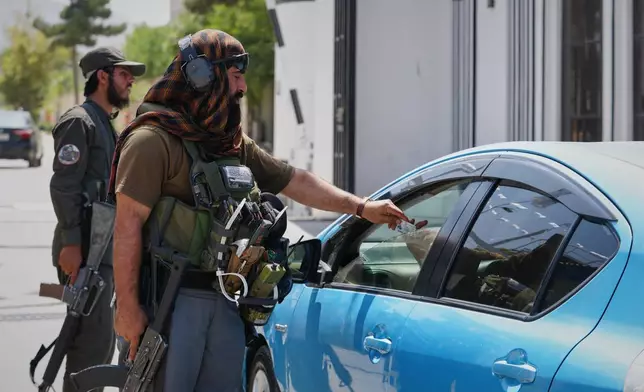 A Taliban security officer checks a driver's identification at a checkpoint ahead of celebrations marking the fifth anniversary of the U.S. withdrawal from Afghanistan and the start of Taliban rule, in Kabul, Afghanistan, Thursday, Aug. 13, 2026. (AP Photo/Siddiqullah Alizai)