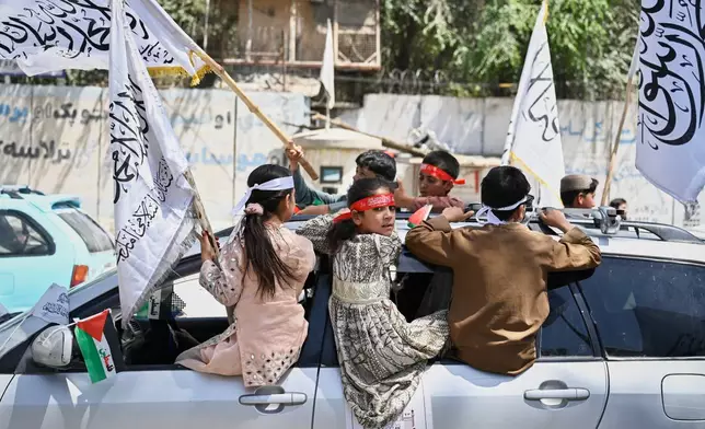 Children ride on a vehicle and wave Taliban flags during celebrations marking the fifth anniversary of the U.S. withdrawal from Afghanistan and the Taliban's return to power, in Kabul, Afghanistan, Saturday, Aug. 15, 2026. (AP Photo/Nava Jamshidi)