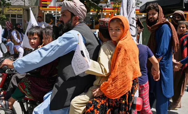 Children ride on a motorcycle carrying Taliban flags during celebrations marking the fifth anniversary of the U.S. withdrawal from Afghanistan and the Taliban's return to power, in Kabul, Afghanistan, Saturday, Aug. 15, 2026. (AP Photo/Nava Jamshidi)