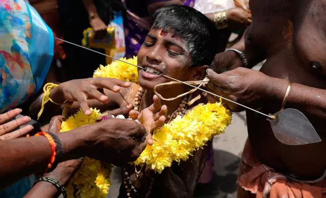 A Hindu devotee reacts in pain after having his cheeks pierced with a steel rod as part of a ritual during the 'Aadi' festival, a holy month for Tamils observed with prayers and offerings to Hindu goddesses, in Chennai, India, Sunday, Aug. 9, 2026. (AP Photo/Mahesh Kumar A.)