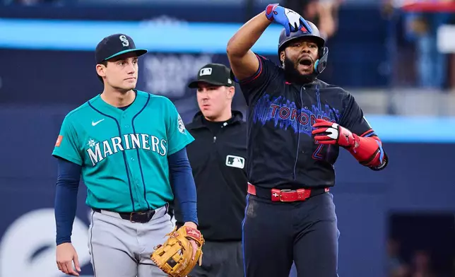 Toronto Blue Jays' Vladimir Guerrero Jr., right, celebrates after hitting an RBI double as Seattle Mariners second baseman Cole Young, left, looks on during the first inning of a baseball game in Toronto, Friday, Aug. 28, 2026. (Sammy Kogan/The Canadian Press via AP)