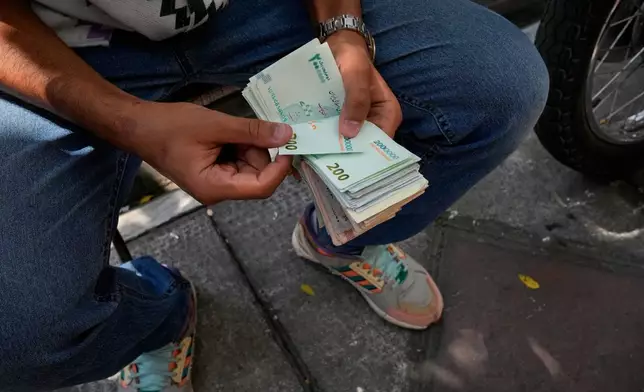 A money exchanger counts Iranian banknotes at Ferdowsi square, Tehran's go-to venue for foreign currency exchange, in downtown Tehran, Iran, Monday, Aug. 24, 2026. AP Photo/Vahid Salemi)