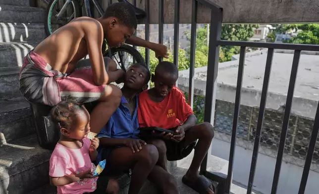 Children watch a movie on a mobile device at a shelter for families displaced by gang violence in Port-au-Prince, Haiti, Wednesday, Aug. 19, 2026. (AP Photo/Odelyn Joseph)